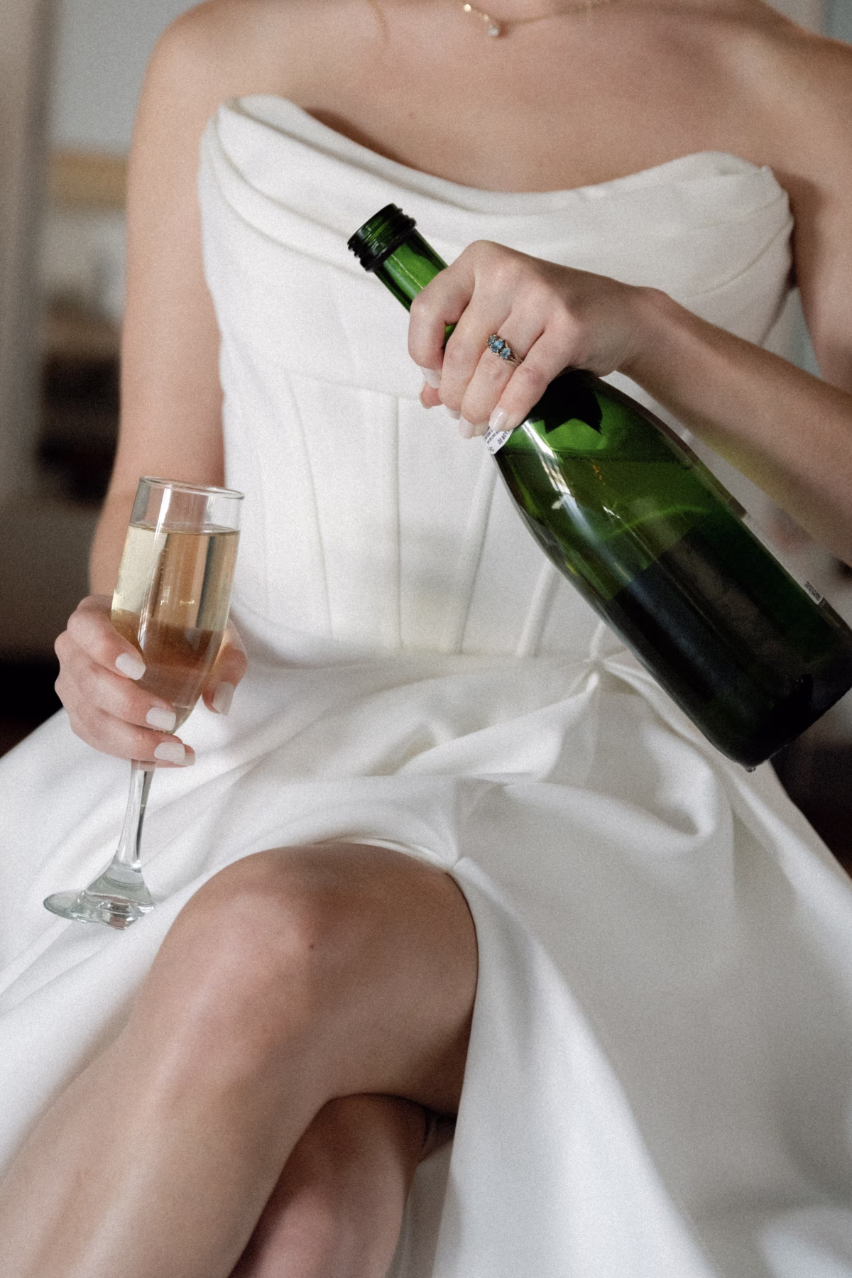 Bride in white gown holding champagne bottle and flute at The Foxwood wedding venue in Hill Country Texas