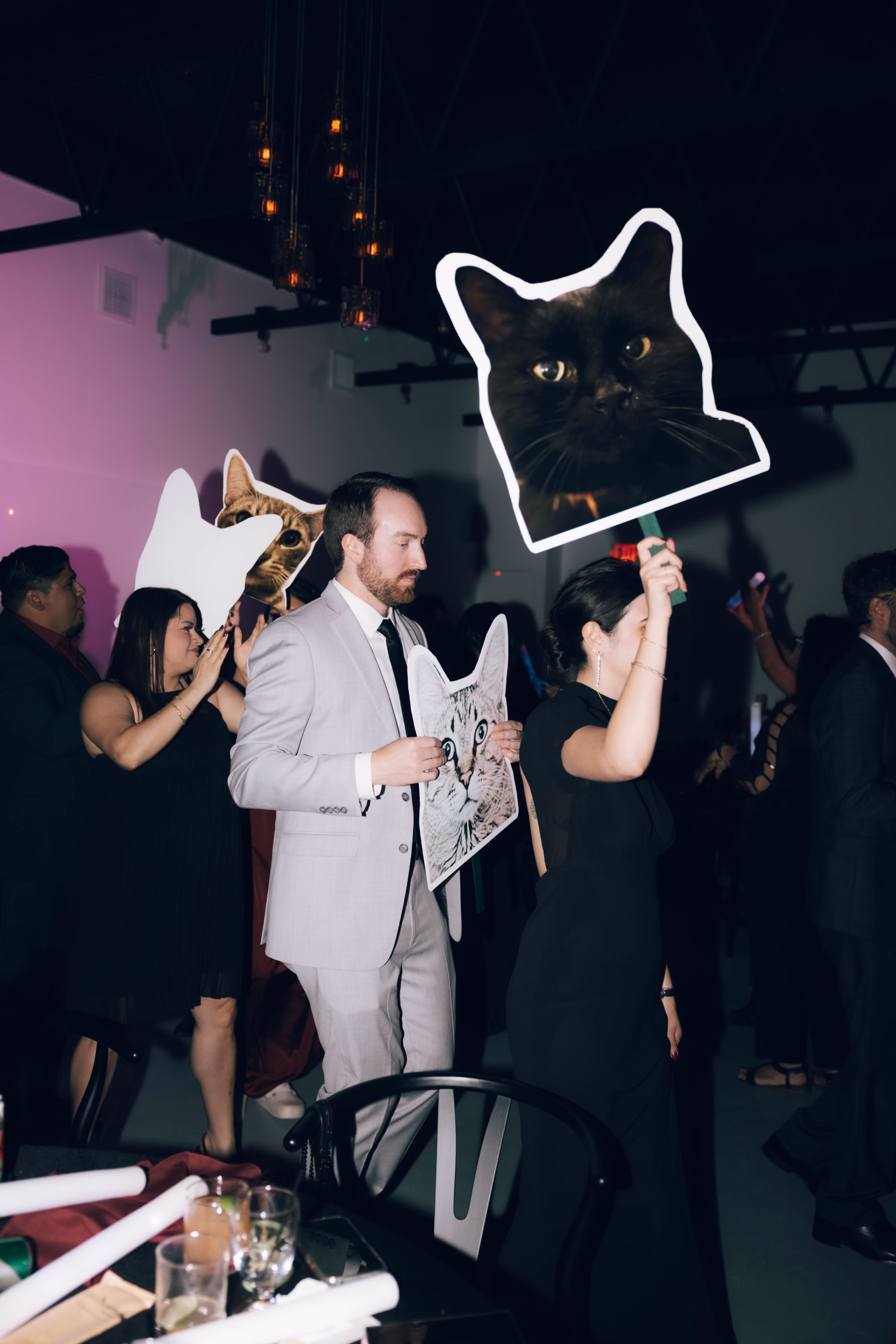 Wedding guests holding whimsical cat photo props during reception at The Foxwood venue in Canyon Lake Texas