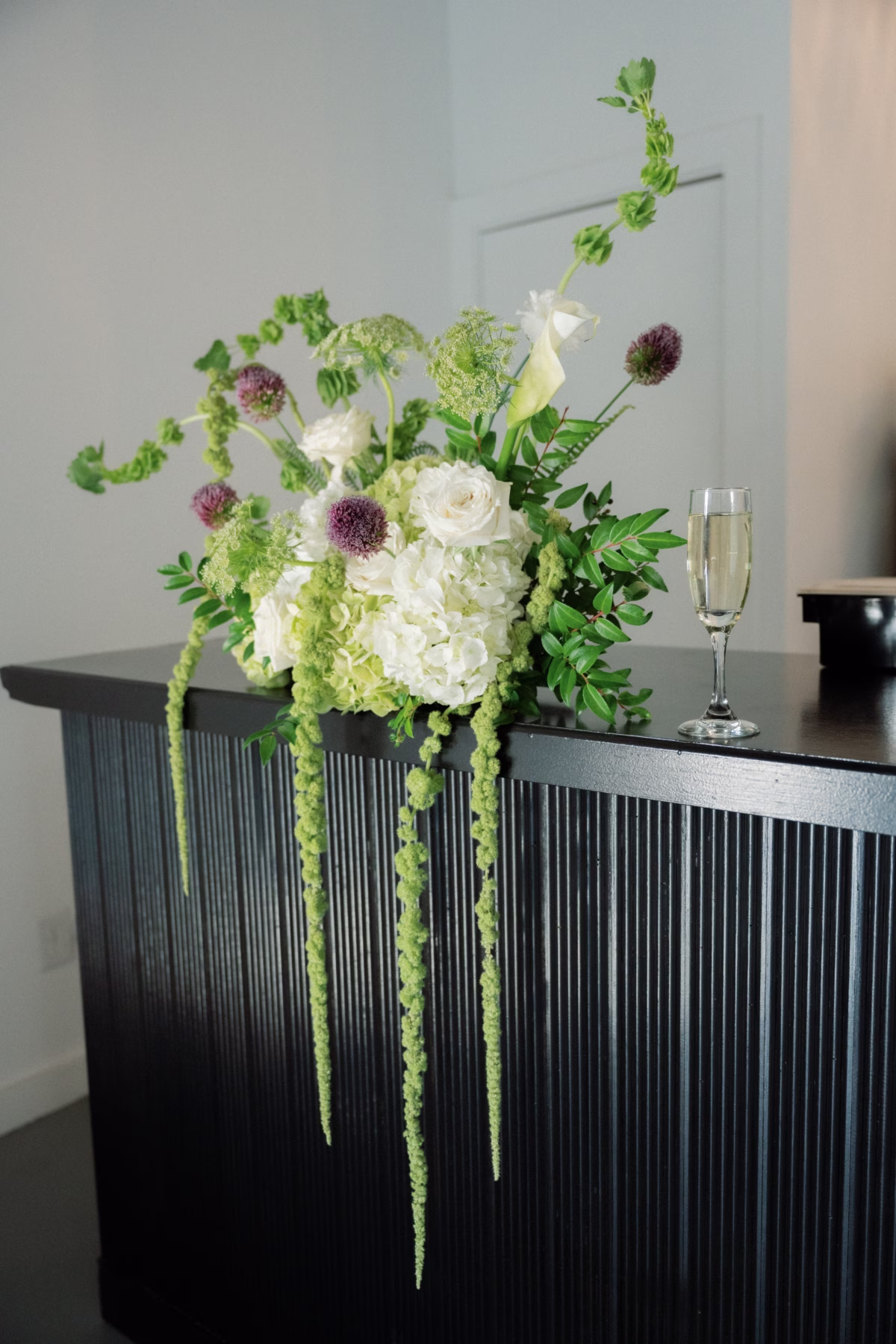 Elegant white hydrangeas and green amaranthus floral arrangement with champagne glass at The Foxwood Hill Country Texas wedding venue