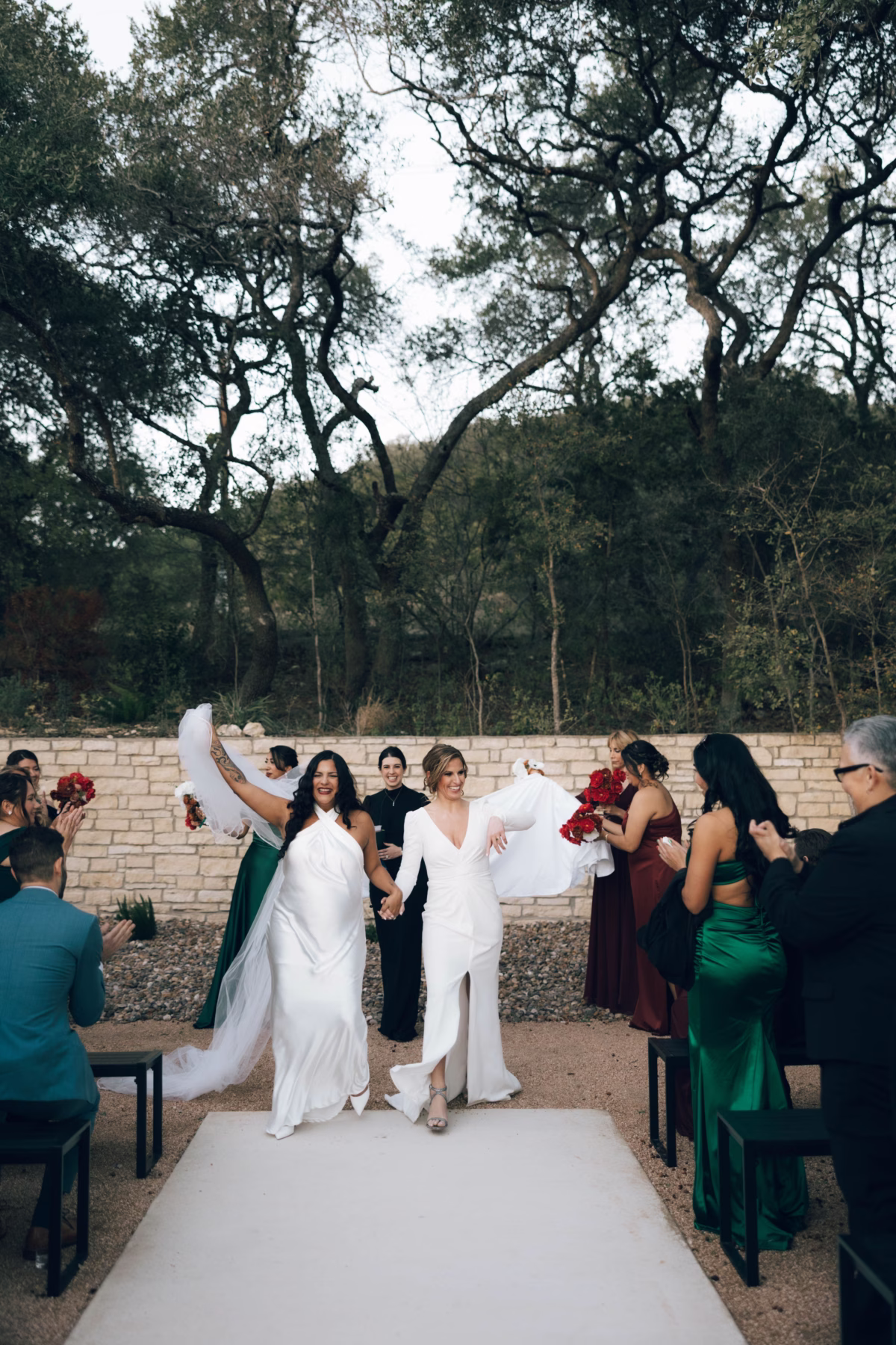 Two brides in white wedding dresses celebrating after their outdoor ceremony at The Foxwood wedding venue in Hill Country Texas