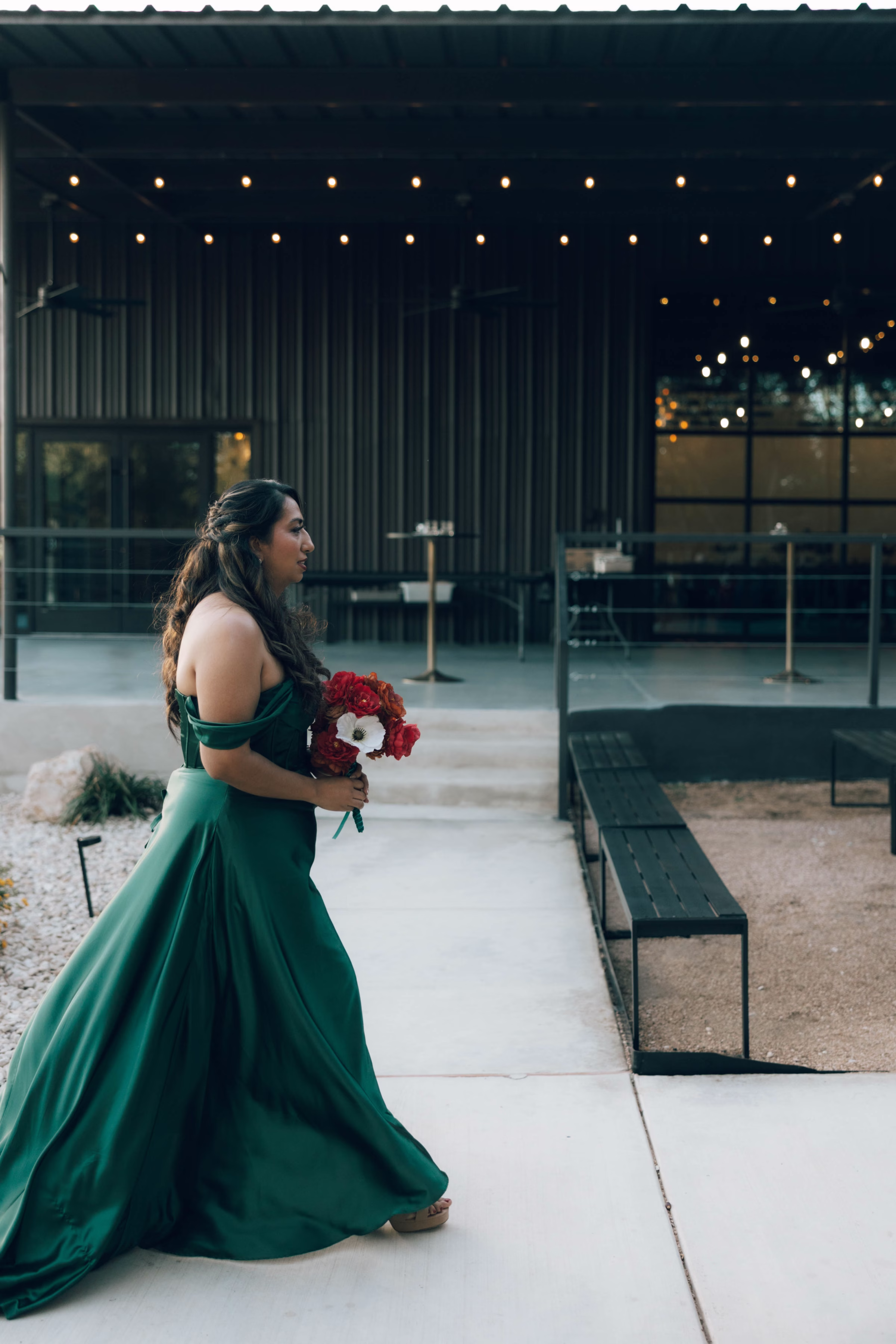 Bridesmaid in emerald green gown holding red and white bouquet at The Foxwood wedding venue in Hill Country Texas