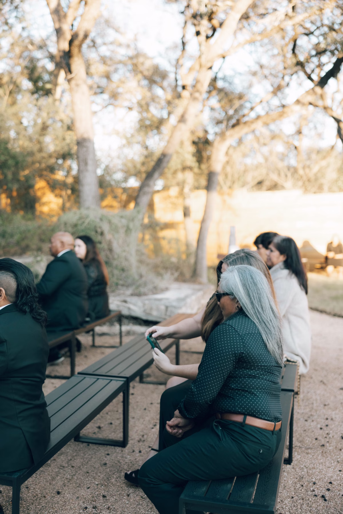 Wedding guests seated at outdoor ceremony tables under trees at The Foxwood Hill Country Texas wedding venue