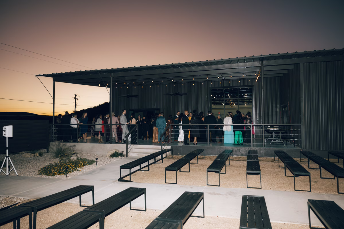Outdoor wedding ceremony setup with wooden benches and string lights at The Foxwood wedding venue in Texas Hill Country at sunset