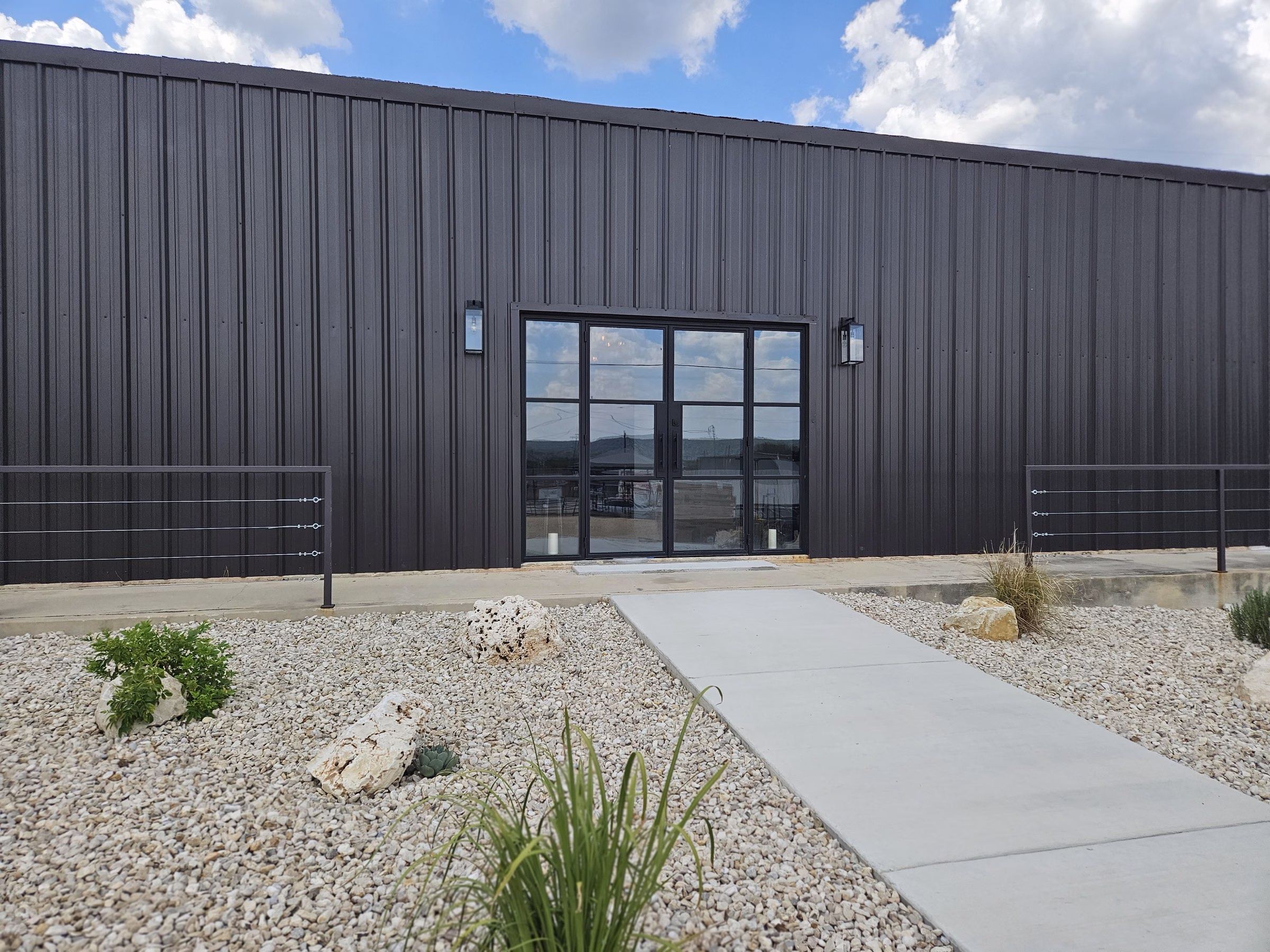 Modern industrial wedding venue exterior with dark metal siding and large glass doors at The Foxwood in Hill Country Texas
