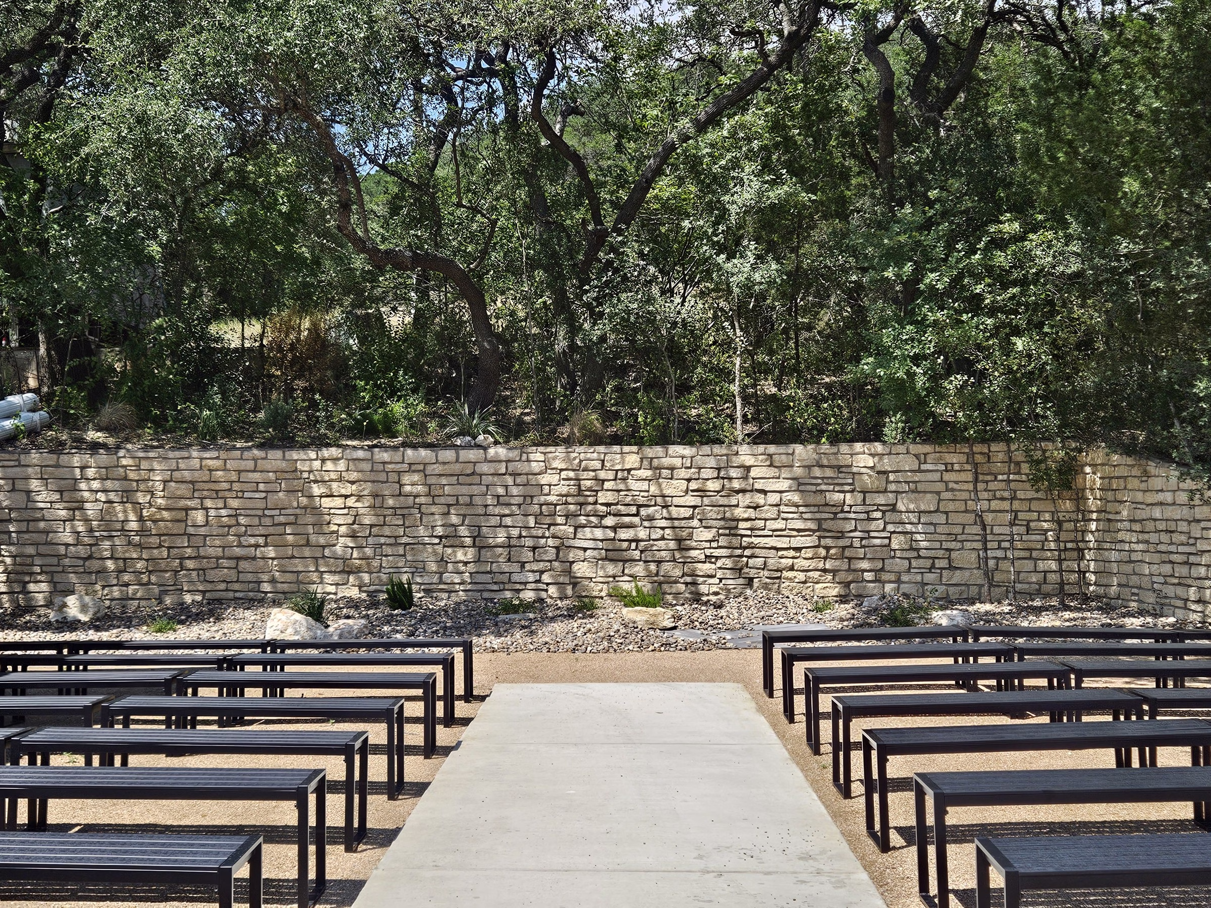 Outdoor wedding ceremony setup with wooden benches and stone wall backdrop at The Foxwood wedding venue in Hill Country Texas