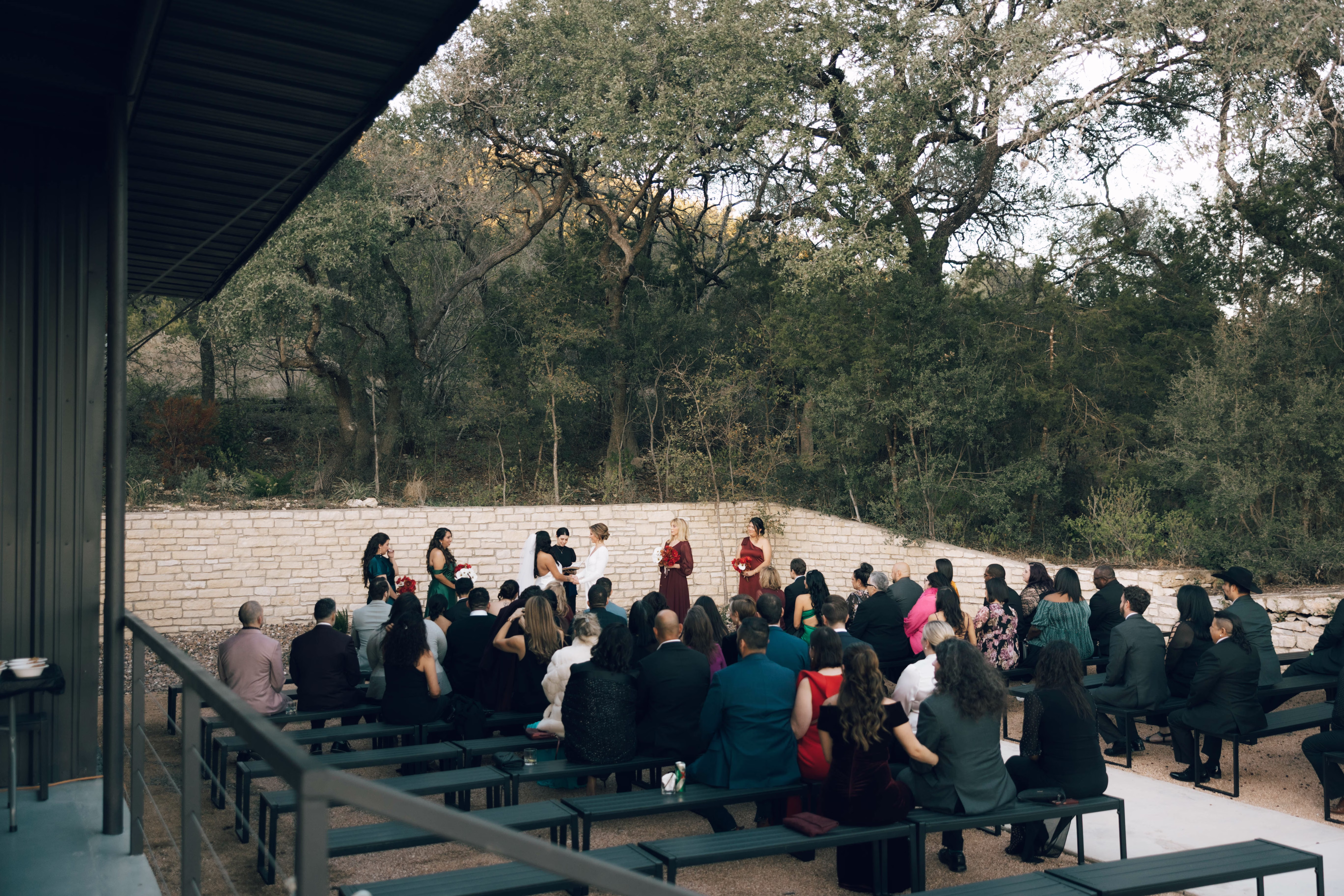 Outdoor wedding ceremony at The Foxwood Hill Country Texas venue with guests seated on benches facing bridal party under covered pavilion surrounded by native trees